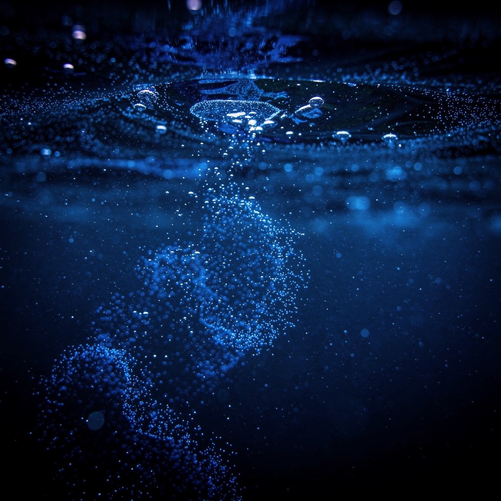 Bioluminescent plankton glowing blue in dark seawater, sparkling particles, macro shot, magical night ocean scene